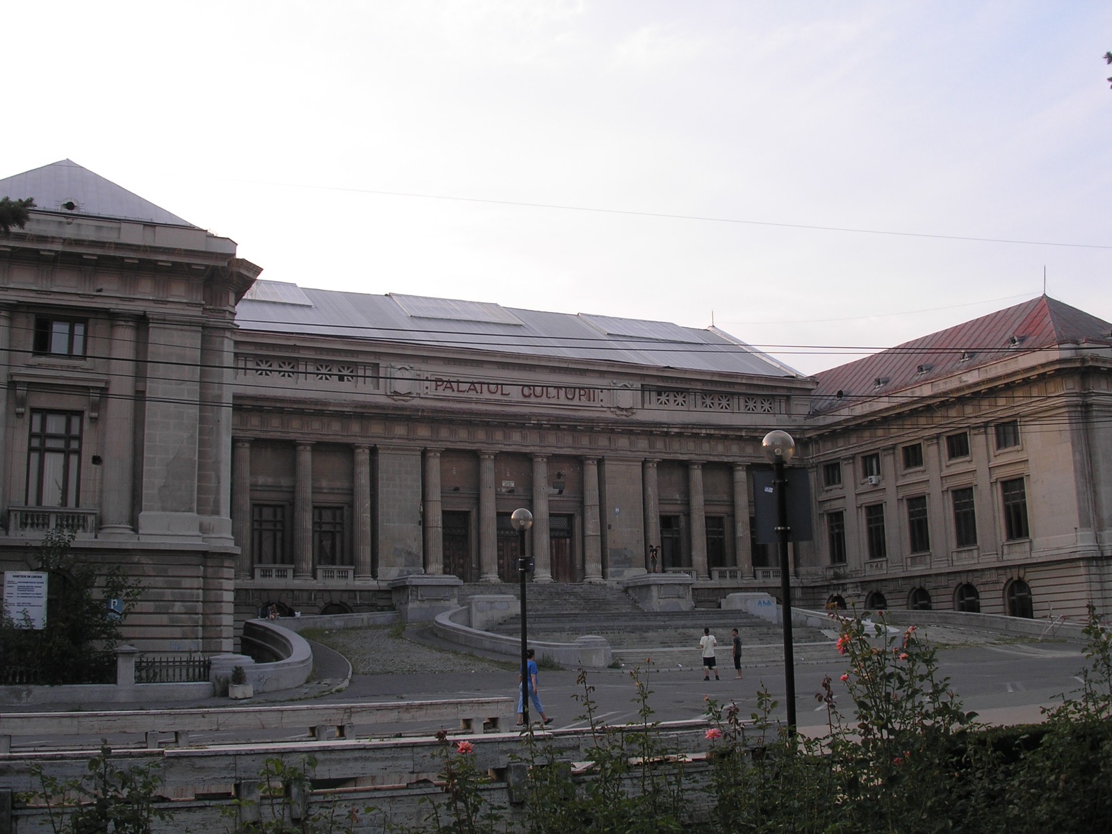 Palatul Culturii văzut oblic, cu scara de la intrare, aripa laterală și acoperișul roșu, sub cer înnorat
