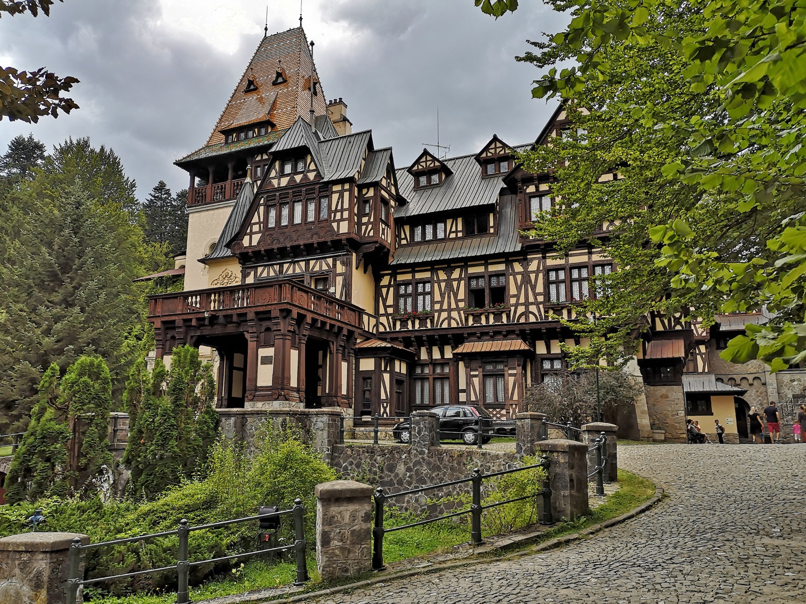 Das Schloss vom gepflasterten Weg aus, der zwischen Bäumen zum Eingang hinaufführt