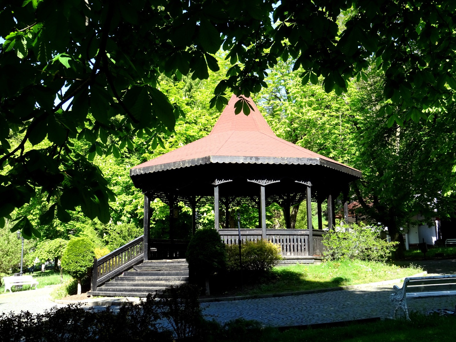 Der hölzerne Pavillon des Parks mit rotem Dach zwischen Kastanienbäumen