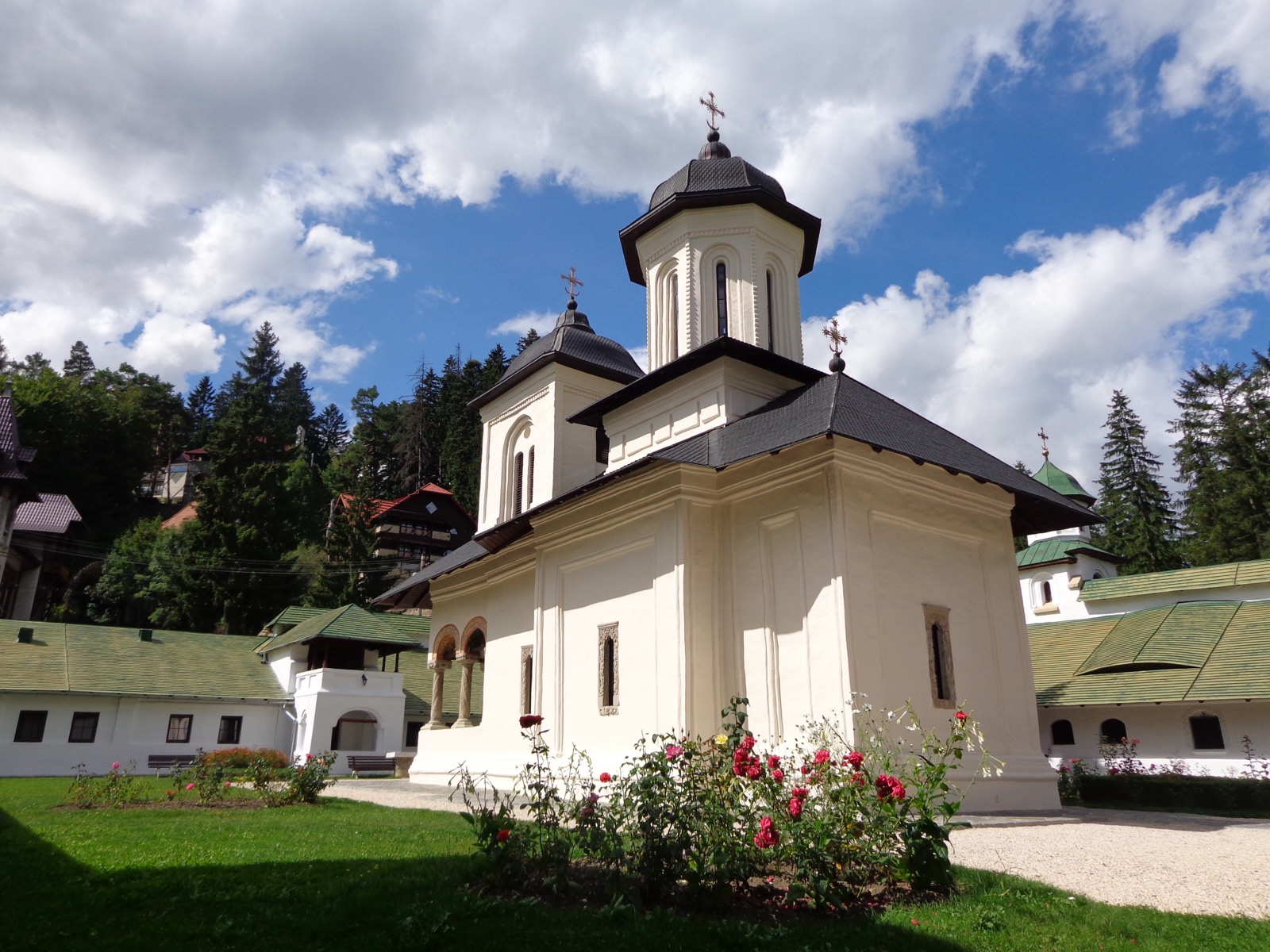 Die weiße alte Kirche Mariä Entschlafung mit zwei Türmen und Rosen davor im alten Hof
